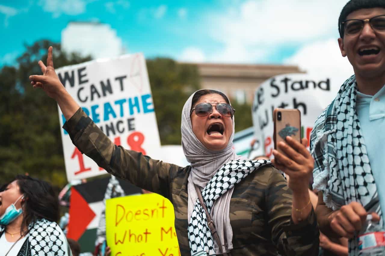 Protesters passionately rally outdoors, holding signs and chanting for justice.